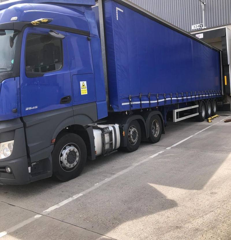 Blue Actros and curtainside trailer reversed onto a warehouse loading dock