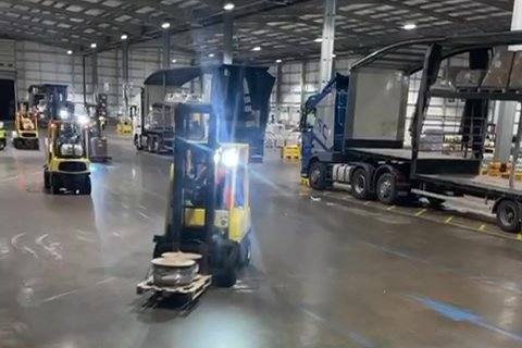 Forklifts working trailers inside a parcel hub at night