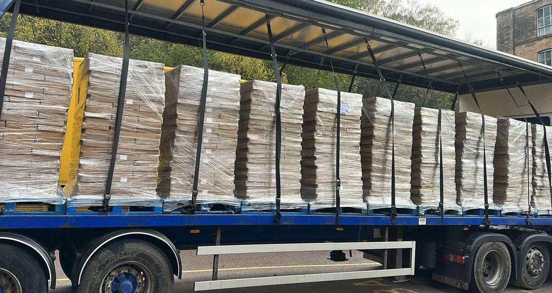 Curtainside trailer opened up with a full row of wrapped pallets strapped down