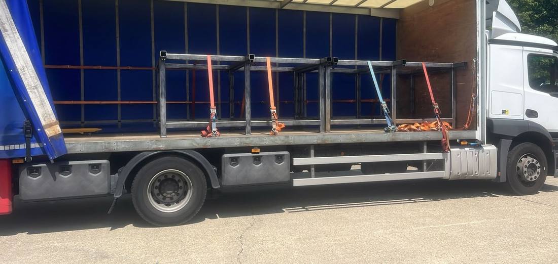 18-tonne Mercedes rigid with the curtain open and steel frames ratchet-strapped to the deck